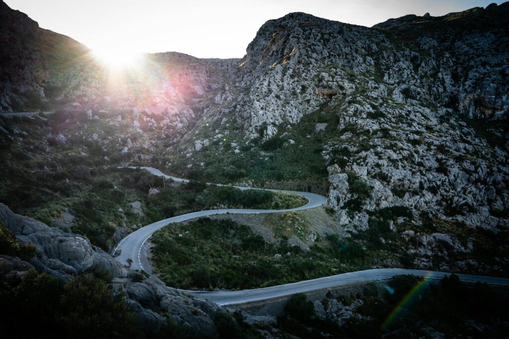 Winding mountain road with rocky landscape at sunrise, perfect for adventure seekers.