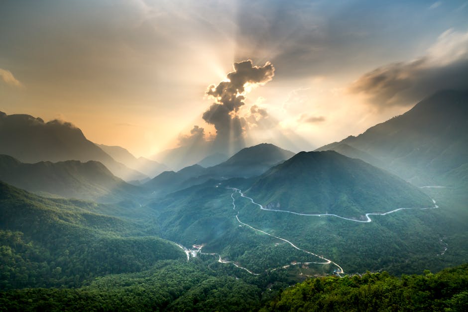 A stunning view of a sunlit mountain landscape showcasing dramatic clouds and winding roads.