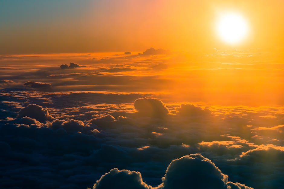 Stunning aerial view of a dramatic sunset over thick clouds, glowing horizon.